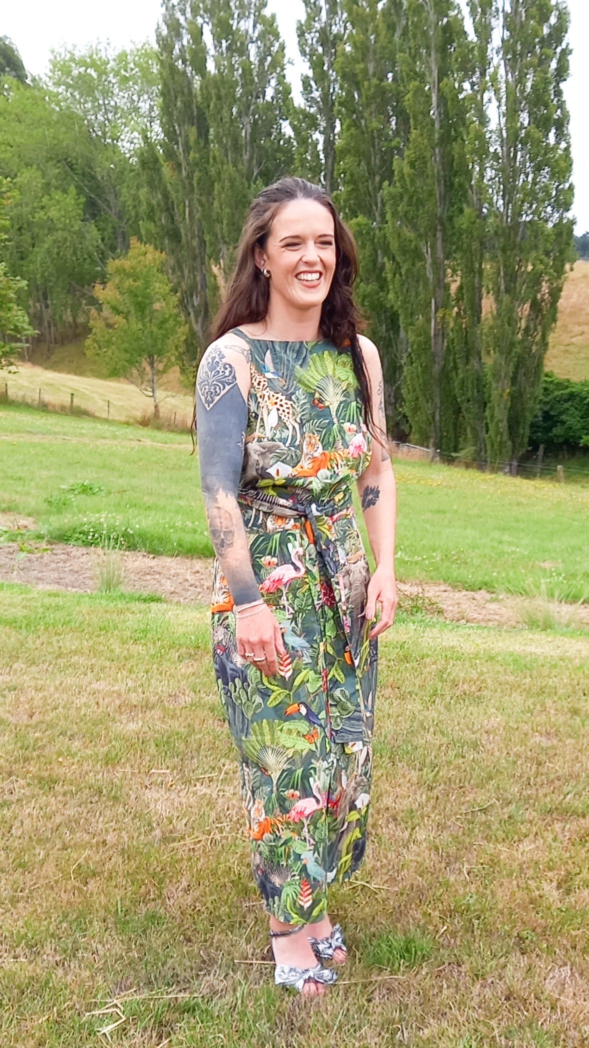 Tattooed woman wearing safari print rental dress set with waist tie and pencil skirt in countryside
