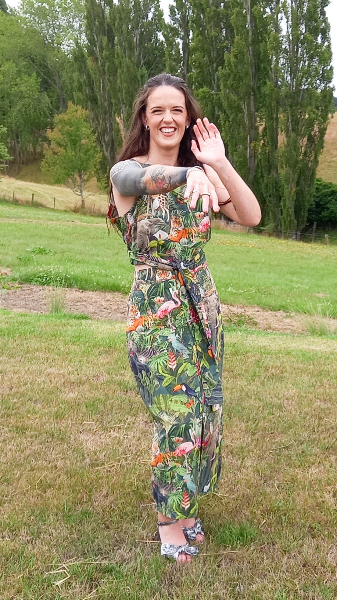 Tattooed woman dancing wearing safari print rental dress set with waist tie and pencil skirt in countryside